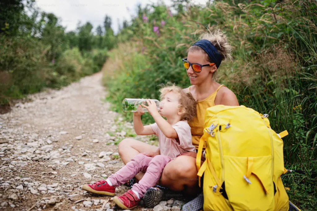 Mother and Child Resting and Drinking Water on Trail